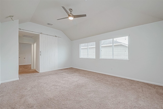 empty room featuring lofted ceiling, ceiling fan, carpet, and visible vents