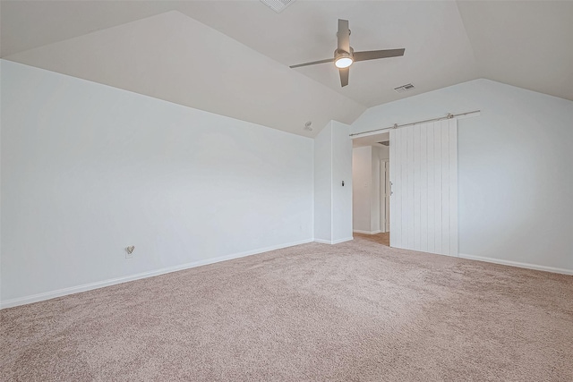 carpeted spare room with lofted ceiling, visible vents, a barn door, ceiling fan, and baseboards