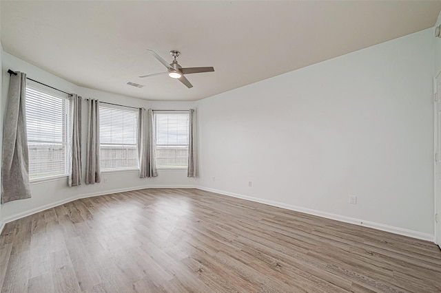 spare room featuring visible vents, wood finished floors, a wealth of natural light, and baseboards