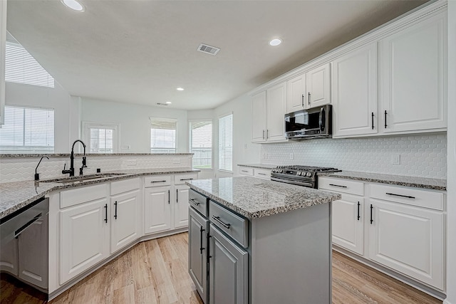 kitchen with visible vents, white cabinets, appliances with stainless steel finishes, gray cabinets, and a sink