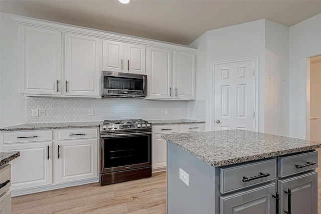 kitchen with light wood finished floors, light stone countertops, gray cabinets, stainless steel appliances, and white cabinetry