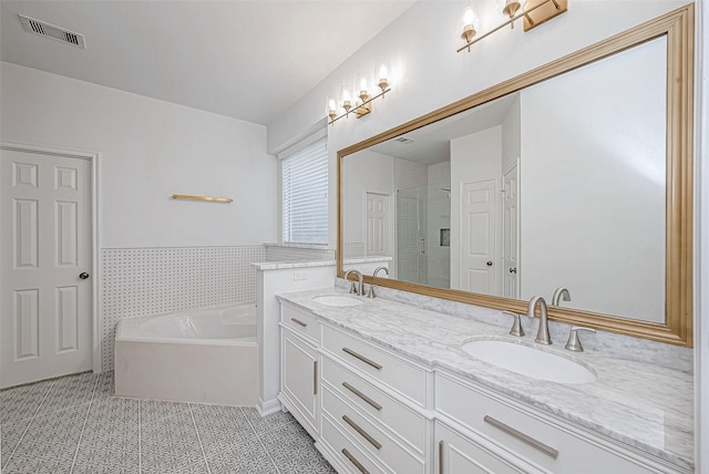 bathroom with a garden tub, visible vents, a sink, and tile patterned floors