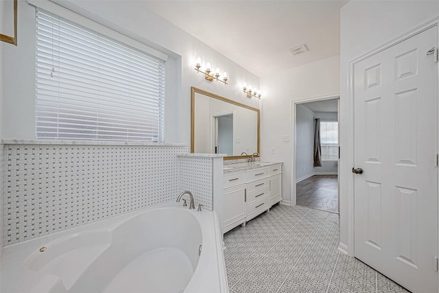 full bathroom with visible vents, a bath, and vanity