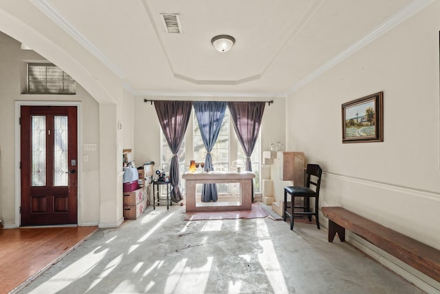 foyer entrance with baseboards, visible vents, wood finished floors, a tray ceiling, and crown molding