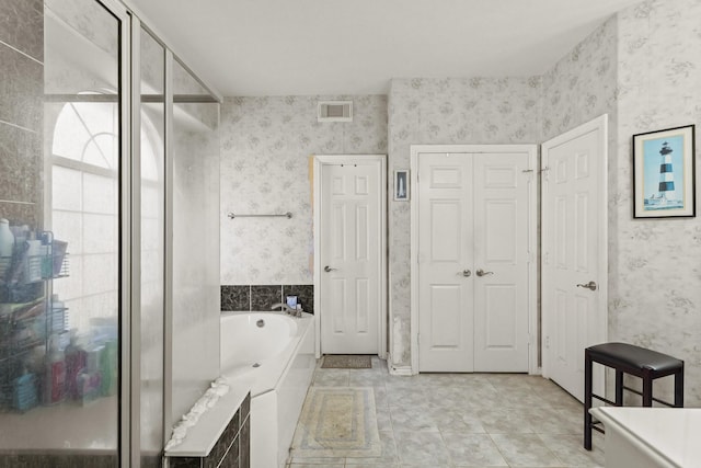 full bath featuring a garden tub, visible vents, a closet, tile patterned floors, and wallpapered walls