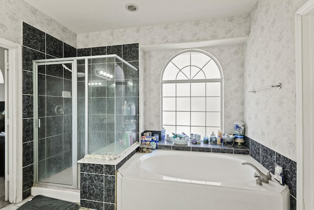 bathroom with a stall shower, a garden tub, and wallpapered walls