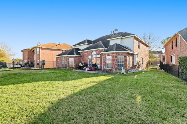 back of house with a yard, brick siding, a patio area, and a fenced backyard