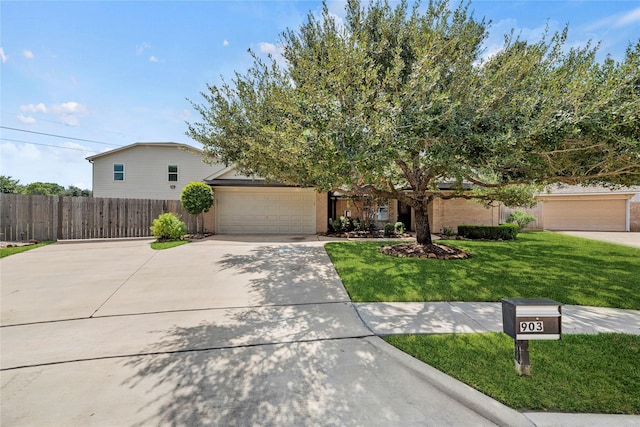 view of front of home featuring a garage, driveway, a front yard, and fence