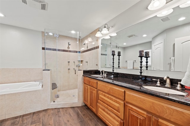 full bath featuring a garden tub, visible vents, a sink, a shower stall, and wood finished floors