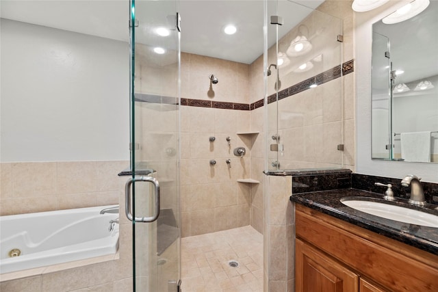 full bathroom featuring a stall shower, vanity, and a tub with jets