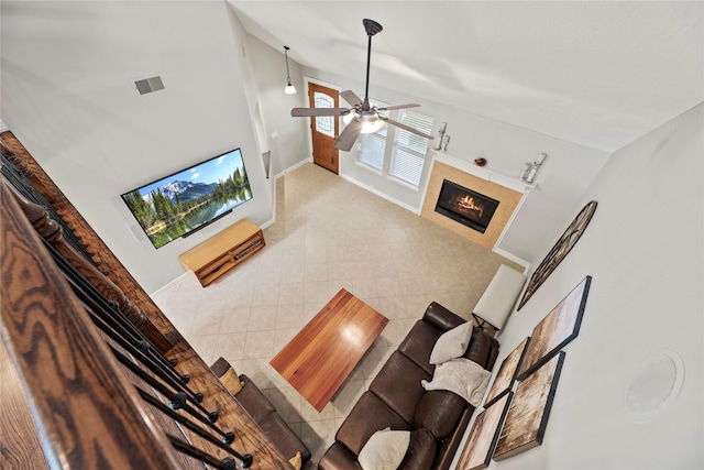 living room with visible vents, baseboards, a ceiling fan, a tiled fireplace, and lofted ceiling