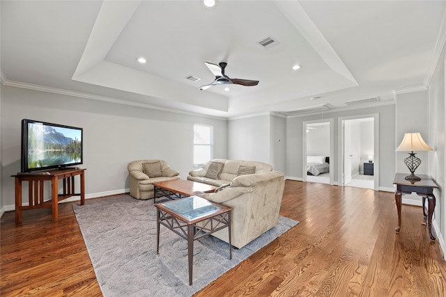 living room with attic access, visible vents, a raised ceiling, and wood finished floors