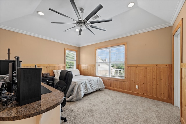 carpeted bedroom with wood walls, wainscoting, visible vents, and crown molding