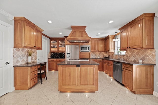 kitchen with glass insert cabinets, appliances with stainless steel finishes, a center island, pendant lighting, and a sink