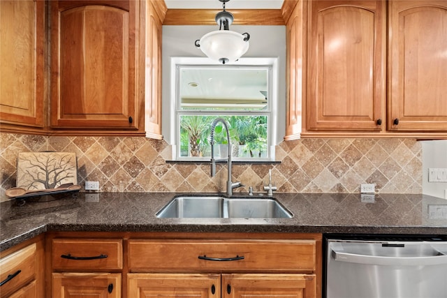 kitchen with brown cabinetry, dishwasher, backsplash, decorative light fixtures, and a sink