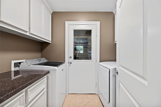 clothes washing area with light tile patterned floors, cabinet space, and separate washer and dryer