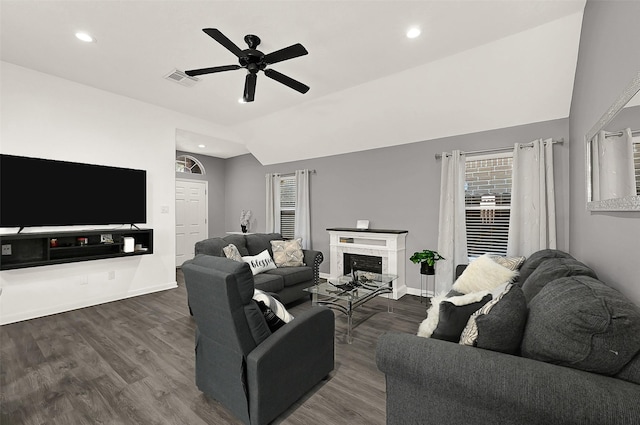 living room featuring baseboards, a ceiling fan, lofted ceiling, dark wood-type flooring, and a brick fireplace