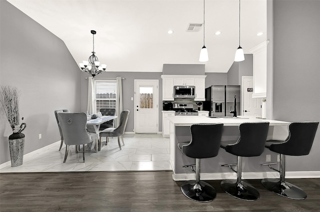 kitchen featuring stainless steel appliances, a sink, white cabinets, light countertops, and decorative light fixtures