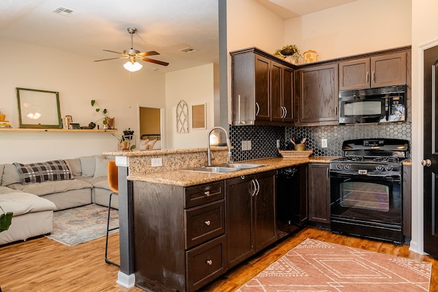 kitchen with open floor plan, black appliances, a peninsula, and a sink