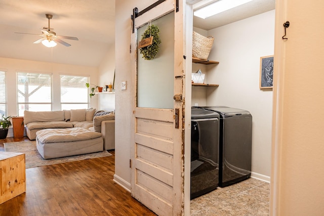 laundry room featuring ceiling fan, a barn door, laundry area, wood finished floors, and washer and dryer