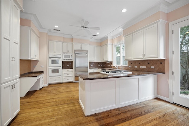 kitchen featuring a peninsula, white cabinetry, and built in appliances