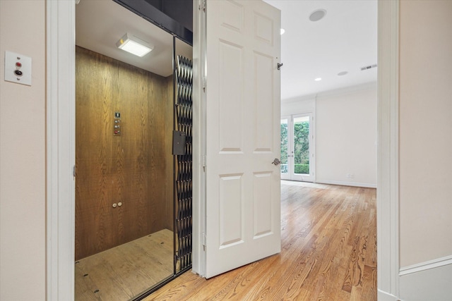 hallway featuring recessed lighting, visible vents, baseboards, light wood-type flooring, and elevator