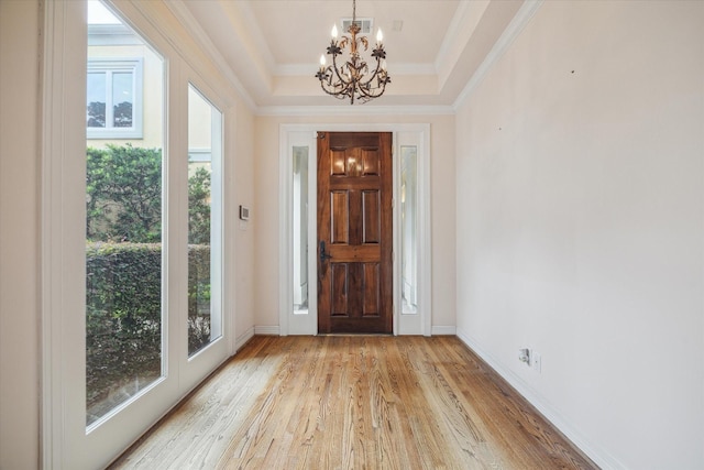 foyer featuring a tray ceiling, a notable chandelier, crown molding, light wood finished floors, and baseboards