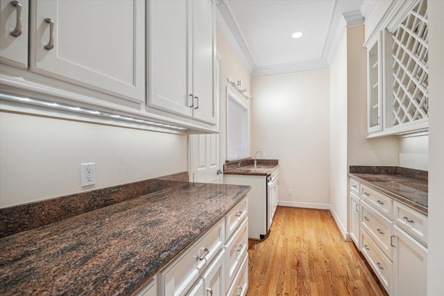 kitchen with glass insert cabinets, white cabinetry, and dark stone countertops