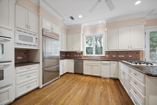 kitchen featuring white cabinets, visible vents, a sink, and built in appliances