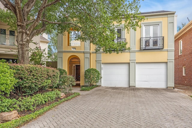 view of front of home featuring decorative driveway, an attached garage, and stucco siding