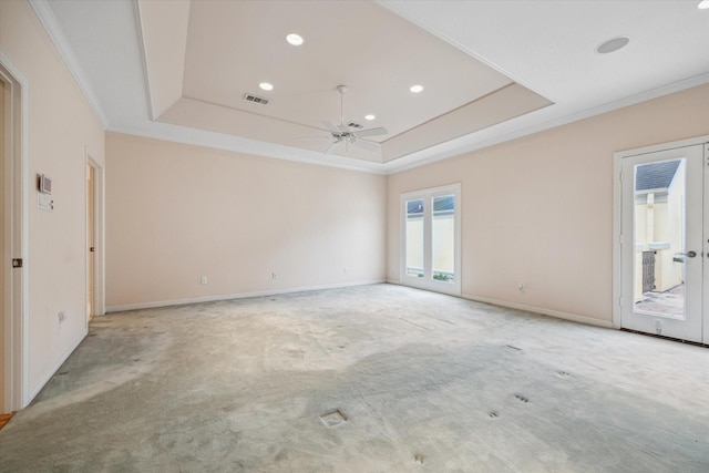 empty room featuring carpet, a tray ceiling, ceiling fan, and ornamental molding