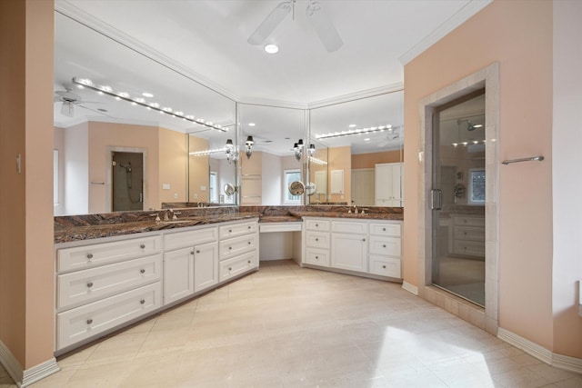 bathroom featuring a ceiling fan, a stall shower, two vanities, and a sink