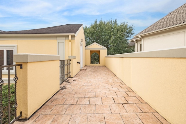 view of home's exterior with roof with shingles, fence, a patio, and stucco siding