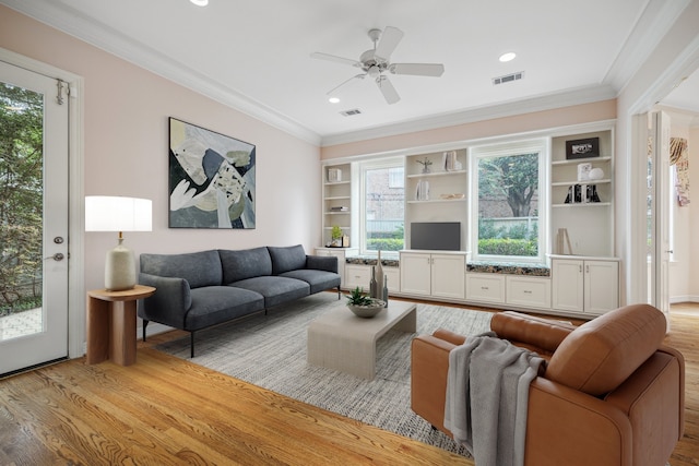 living room featuring a ceiling fan, visible vents, crown molding, and light wood-style flooring