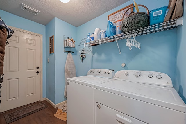 washroom featuring laundry area, visible vents, wood finished floors, a textured ceiling, and washer and dryer