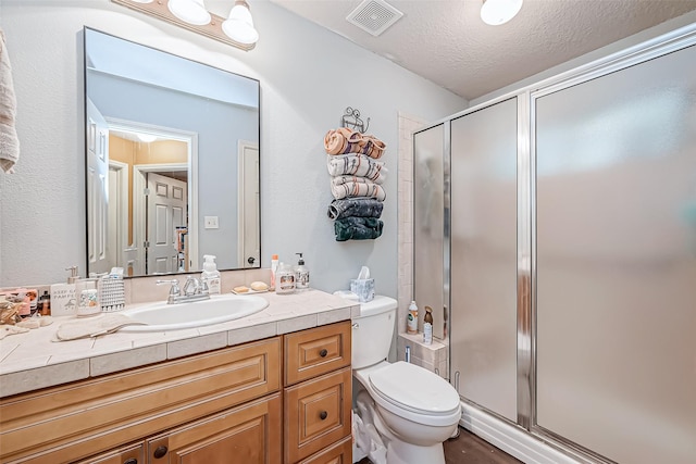 full bathroom with toilet, a stall shower, visible vents, and a textured ceiling