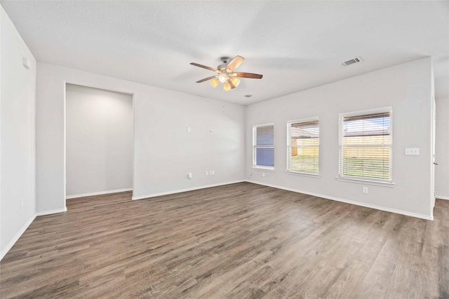 unfurnished room featuring ceiling fan, dark wood finished floors, visible vents, and baseboards