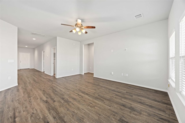 empty room with plenty of natural light, dark wood finished floors, visible vents, and baseboards