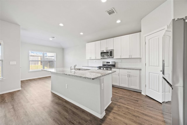 kitchen featuring stainless steel appliances, a sink, visible vents, white cabinetry, and a center island with sink