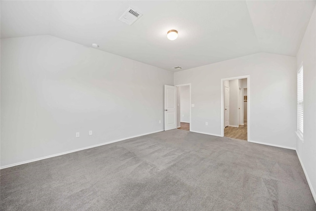 unfurnished bedroom featuring baseboards, visible vents, vaulted ceiling, and carpet flooring