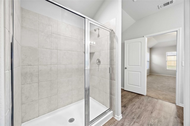 full bath with a stall shower, baseboards, visible vents, lofted ceiling, and wood finished floors