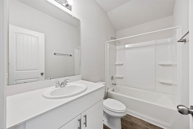 full bathroom with a textured wall, toilet, wood finished floors, vanity, and  shower combination