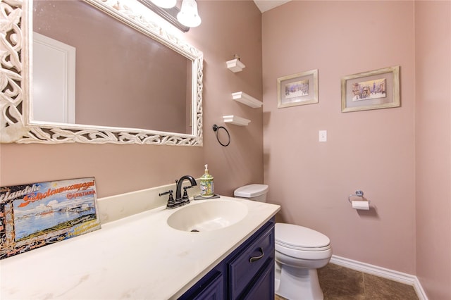 half bathroom with baseboards, vanity, toilet, and tile patterned floors