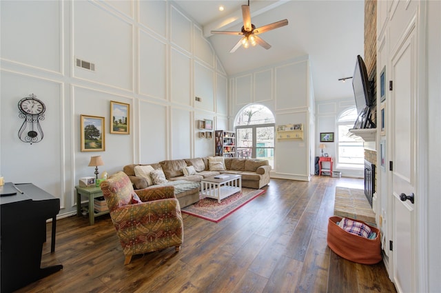 living area featuring high vaulted ceiling, visible vents, and a decorative wall