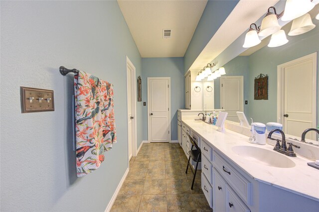 bathroom featuring double vanity, a sink, visible vents, and baseboards