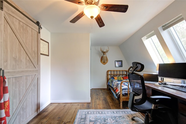 bedroom with lofted ceiling with skylight, a barn door, a ceiling fan, and hardwood / wood-style floors