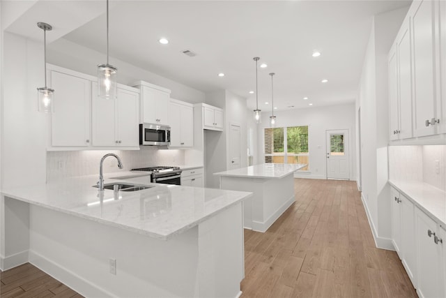 kitchen with a sink, light wood-type flooring, a kitchen island, and stainless steel appliances