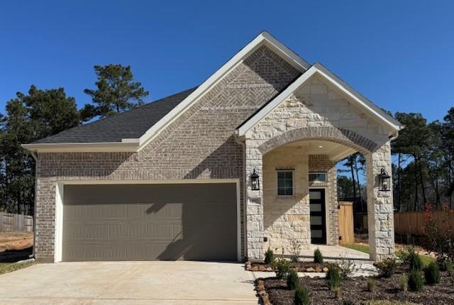 french country style house featuring brick siding, stone siding, concrete driveway, and a garage