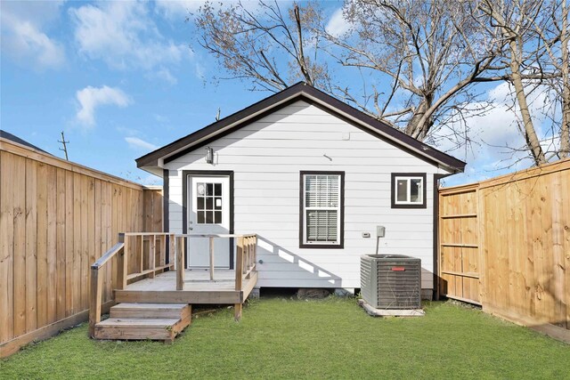 rear view of property with a fenced backyard, a lawn, and central AC unit