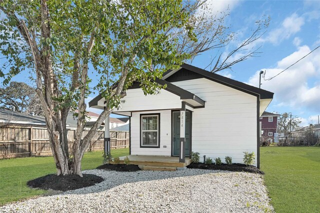 bungalow-style home with fence and a front lawn